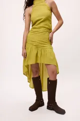 Falda azul con corte irregular, más corta en el frente y más larga en la parte trasera. Presenta volados en la parte inferior y frunces en la cintura.