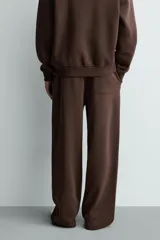 Pantalón jogger de corte relajado y pernera ancha, confeccionado en tejido de algodón con interior perchado. Presenta cintura elástica con cordón interior, bolsillos laterales y un bolsillo trasero de plastrón.