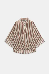Camisa de cuello solapa con escote en pico, manga tres cuartos con vuelta y bajo asimétrico con pliegues delanteros que generan un efecto abullonado.