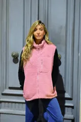 Chaleco de corderito color rosado, con cuello alto, cierre frontal y un bolsillo con cierre en el pecho.