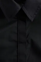 Camisa de manga corta de popelina de algodón en color negro, con cuello camisero, botonadura oculta y diseño con peplum acampanado en la cintura.
