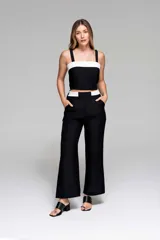 Pantalón negro de pierna ancha con cintura bicolor y bolsillos laterales.