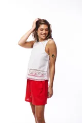 Blusa blanca sin mangas con detalles de encaje en el ruedo y los hombros.