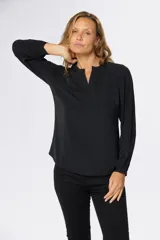 Blusa de manga larga en color azul marino, con escote en V y diseño de doble capa en el frente. Presenta puños elásticos y un pequeño aplique metálico decorativo en el ruedo.