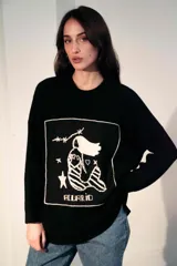 Sweater de punto oversize color crudo, con cuello redondo y diseño bordado a mano en el frente representando al signo Cáncer con un cangrejo, un corazón y una estrella.
