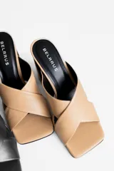 Sandalias de tacón color beige, con tiras cruzadas en el empeine y tacón geométrico negro.