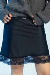 Minifalda de satén negro con detalle de encaje en el borde inferior.