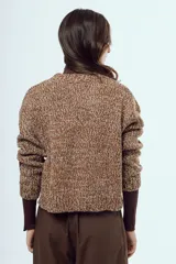 Sweater tejido de punto con acabado moteado en tonos marrones y blancos, de silueta relajada, manga larga y cuello redondo.