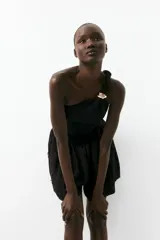 Top corto negro de un hombro en punto con textura. Modelo de ajuste ceñido con escote asimétrico y hombro de diseño girado con detalle metálico dorado adelante. Frunces laterales y bajo recto.