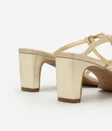Sandalia mule dorada con punta cuadrada, tiras finas con detalle de lazos y tacón cuadrado mediano.