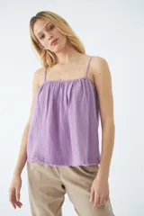 Blusa de tirantes finos ajustables, con diseño holgado y ruedo desflecado. Confeccionada en tela de textura arrugada.