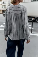 Blusa de manga larga con cuello redondo y escote en pico, cierre frontal con botones y diseño de rayas verticales.