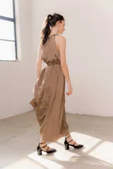 Vestido largo color marrón de crepé plissé, con escote halter adornado con detalles de perlas, silueta fluida y lazo ajustable en la cintura.