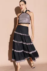 Falda larga de lino color negro con diseño de volados horizontales en tela brillante plateada. Presenta una silueta fluida y cintura alta.