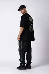 Remera de corte oversize color negro, con cuello redondo y mangas cortas. Presenta un pequeño estampado en color blanco en la parte inferior lateral con la frase 'Curbside Treasures'.