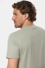 Remera de manga corta color gris con estampado de paisaje costero con palmeras y tablas de surf.