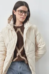Campera puffer negra con diseño acolchado, capucha integrada y cierre frontal con botones a presión. Presenta puños elásticos y costuras decorativas en el frente.
