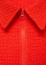 Vestido corto de tejido con textura, color naranja, con cuello polo y cierre de cremallera frontal. Presenta un diseño entallado y mangas cortas.