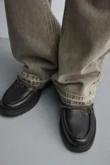 Zapato tipo náutico color negro, con parte superior lisa, bordón y horma redonda. Cuenta con suela de volumen y piso track.