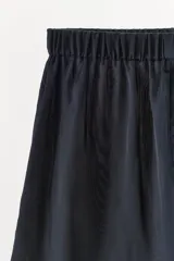 Short liso de tejido satinado color azul marino, de tiro medio con cintura elástica y botones frontales ocultos bajo sopata.
