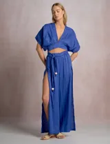 Pantalón palazzo de lino color azul, de tiro alto con cintura elastizada y cinto lazo incorporado con cuentas decorativas en las puntas. Presenta aberturas laterales pronunciadas en las piernas y corte amplio.