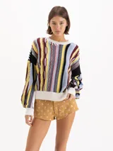 Sweater de tejido semi pesado en mezcla de algodón y lana, de calce oversize y hombros caídos, con cuello redondo y mangas largas. Destaca por su diseño jacquard multicolor con patrones texturizados y rayas verticales.