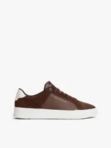 Zapatillas de corte bajo Tommy Hilfiger confeccionadas en una combinación de piel nobuk y piel lisa en color marrón. Presentan suela de goma blanca, detalle de ventilación lateral, logo de la marca en la lengüeta, lateral y talón, y cierre mediante cordones.