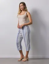 Pantalón capri de lino estampado con rayas verticales en tonos rosa, gris y amarillo. Tiene pretina ancha elastizada, bolsillos inclinados en la parte delantera y cordón ajustable en la cintura.