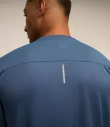 Remera deportiva de poliéster color gris claro, con cuello redondo, mangas cortas y recortes laterales de poliamida. Corte clásico.