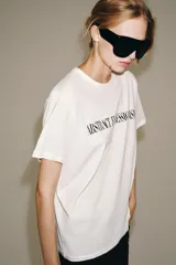 Camiseta oversize blanca de manga corta y cuello redondo, confeccionada en hilatura de algodón con detalle de texto estampado en contraste en el pecho.