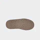 Zuecos UGG modelo Tazz de gamuza color marrón, con suela de plataforma alta y detalle de trenzado decorativo en el borde superior.