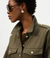 Campera parka Marfinno verde militar de sarga de algodón, con cuello camisero, bolsillos utilitarios con solapa en el pecho y los costados, cierre frontal con botones dorados y cinturón incorporado con hebilla metálica.