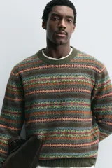 Jersey de punto con diseño jacquard geométrico de rayas horizontales en tonos tierra, verde y naranja. Presenta cuello redondo, manga larga y terminaciones en rib acanalado.