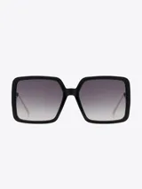 Lentes de sol Carolina Lemke de marco cuadrado negro con lentes degradadas de gris oscuro a transparente.