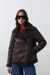Campera tipo gamulán de símil cuero color marrón oscuro, con interior y solapas de corderito al tono. Presenta cierre frontal cruzado, bolsillos con cierre metálico y hebilla ajustable en el cuello.