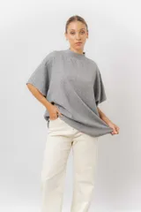 Sweater de tejido de punto color negro, con cuello semi alto y mangas cortas amplias. Presenta una silueta relajada y caída fluida.