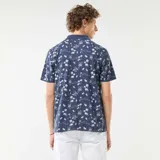 Remera polo azul marino con estampado de palmeras, barcos y paisajes playeros en blanco. De corte clásico y manga corta.