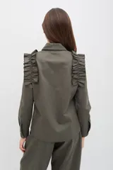 Camisa de gabardina de tencel color negro, con cuello clásico, cierre frontal de botones y volados fruncidos en los hombros.