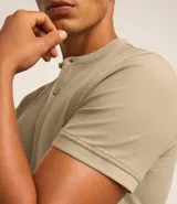 Polo de hombre de manga corta, color beige claro, con cuello mao y tapeta de dos botones.