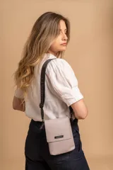 Phonebag pequeña color mostaza, confeccionada en cuero sintético, con solapa frontal y correa ajustable con logo de la marca.