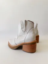 Botas texanas de cuero color gris claro, con caña baja, puntera cuadrada y taco de madera.