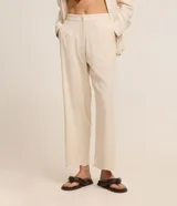 Pantalón recto de cintura alta, color beige, confeccionado en viscolino con detalle de textura perforada con diseño de palmeras en el bajo. Cuenta con elástico en la parte posterior de la cintura y cierre frontal tradicional.
