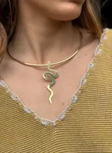 Gargantilla dorada rígida con dije colgante en forma de serpiente.