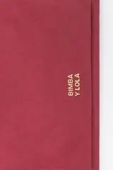 Billetera de estructura blanda confeccionada en nylon negro, con cierre de cremallera superior y bolsillo frontal con cierre. Presenta logo metálico dorado en el frente.