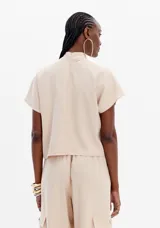 Blusa beige de manga corta con cuello alto.