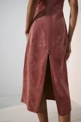 Vestido midi de piel color rosado, con cuello redondo y diseño sin mangas. Presenta costuras marcadas y cierre en la espalda con cremallera oculta.