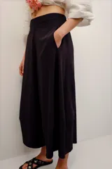 Pantalón babucha color negro, de corte amplio y largo midi, con cintura elástica y bolsillos laterales.