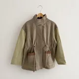 Chaqueta de silueta relajada combinada en paño de lana y pana de algodón, con cuello alto, bolsillos amplios y cordón regulable en la cintura.