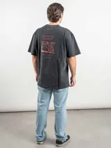 Remera oversize de algodón color negro con efecto lavado. Presenta un estampado gráfico en la espalda con la frase 'Freeze the moment' y un diseño de cámara fotográfica en tonos rojizos.