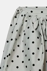 Falda midi de tiro medio, color gris claro con estampado de lunares negros. Presenta cintura ajustable con lazada y bolsillos laterales ocultos.